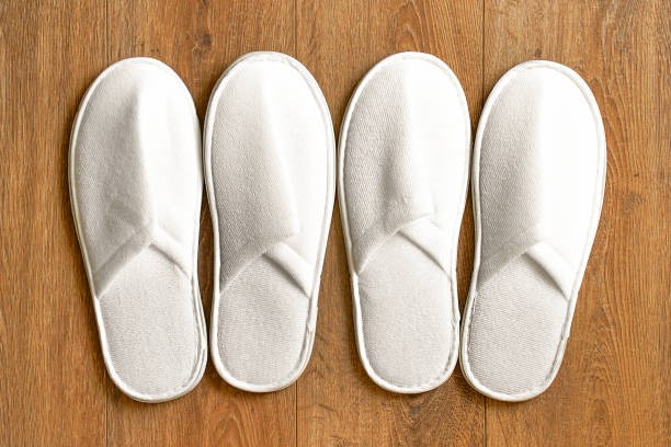 top-view-two-pairs-white-slippers-in-the-hotel-on-wooden-floor-picture-id1182076860